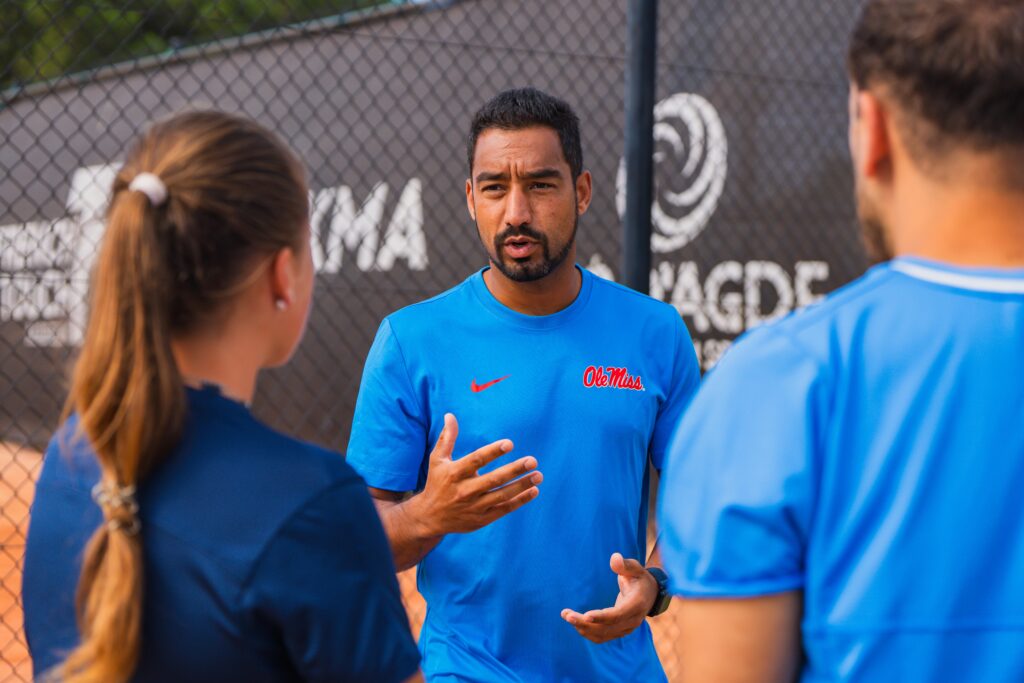 A university coach wearing Ole Miss colors talking with two Tennis Showcase 2026 participants.