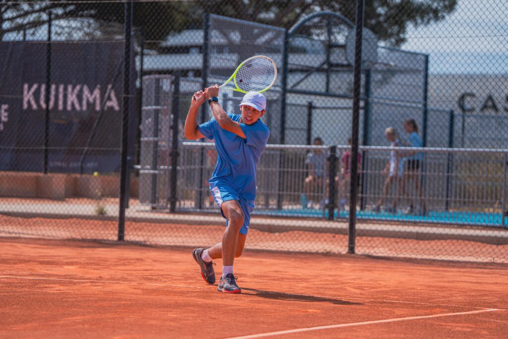 A player hitting a two-handed backhand on clay during the Tennis Showcase 2026.