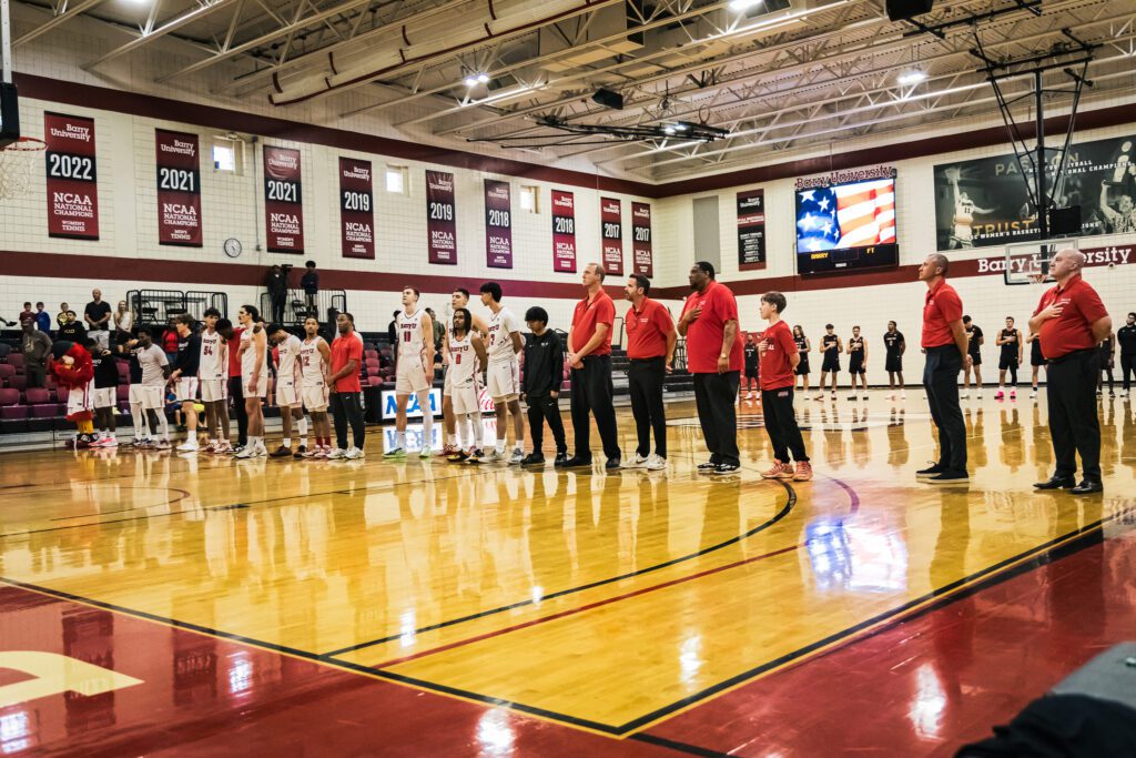 NCAA college basketball players and coaches before a game, illustrating the context of the Five-for-Five eligibility reform.