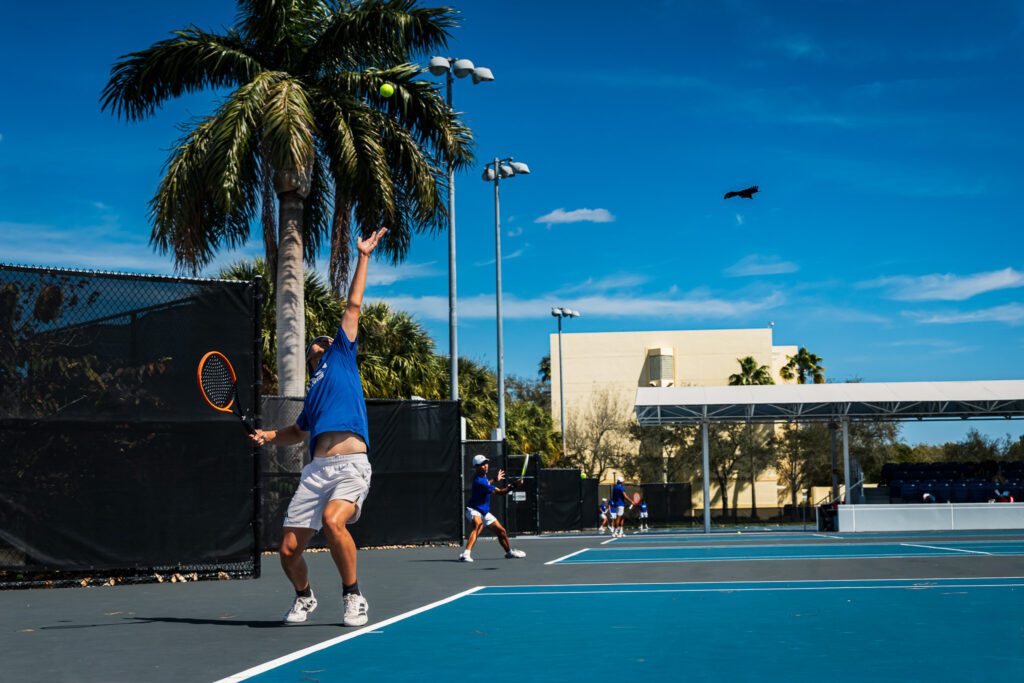 Player serving during a tennis session on a court in Florida at Lynn University