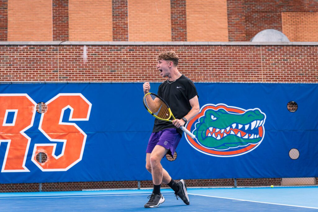 Tennis player celebrating a point in front of the Florida Gators logo